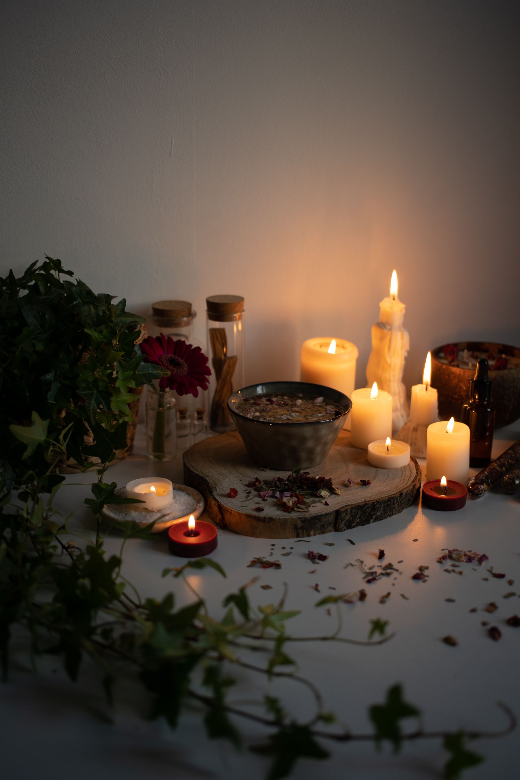 A bowl of herbs surrounded by burning candles