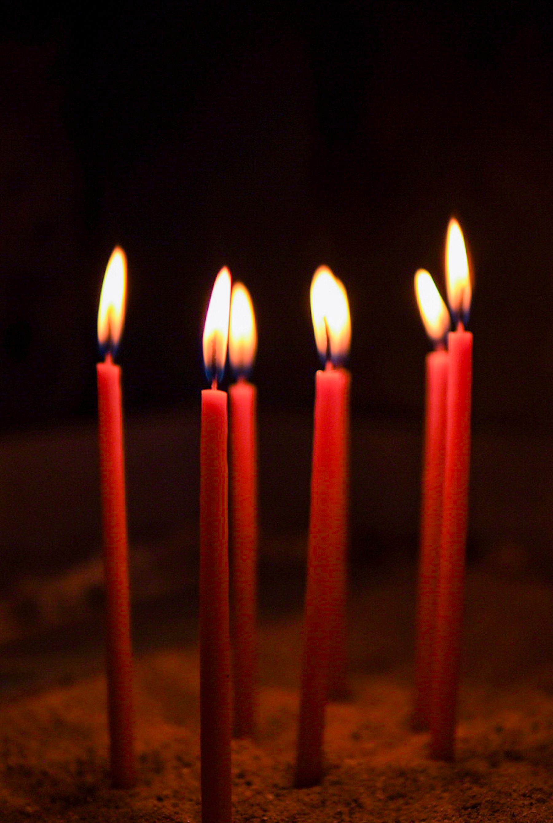 Tall red candles burning in a dim room