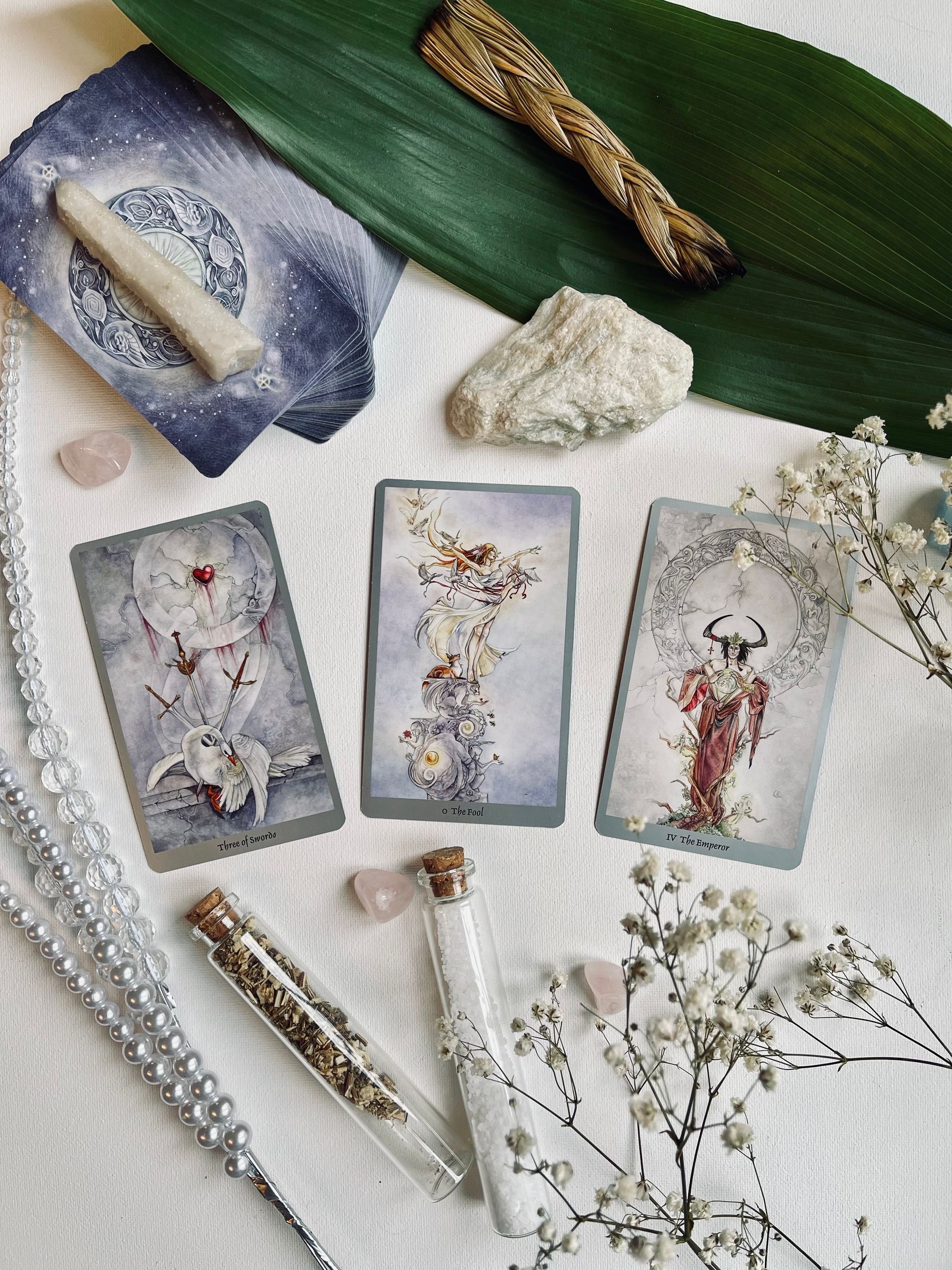 Tarot cards laid on linen beside dried herbs and raw crystals