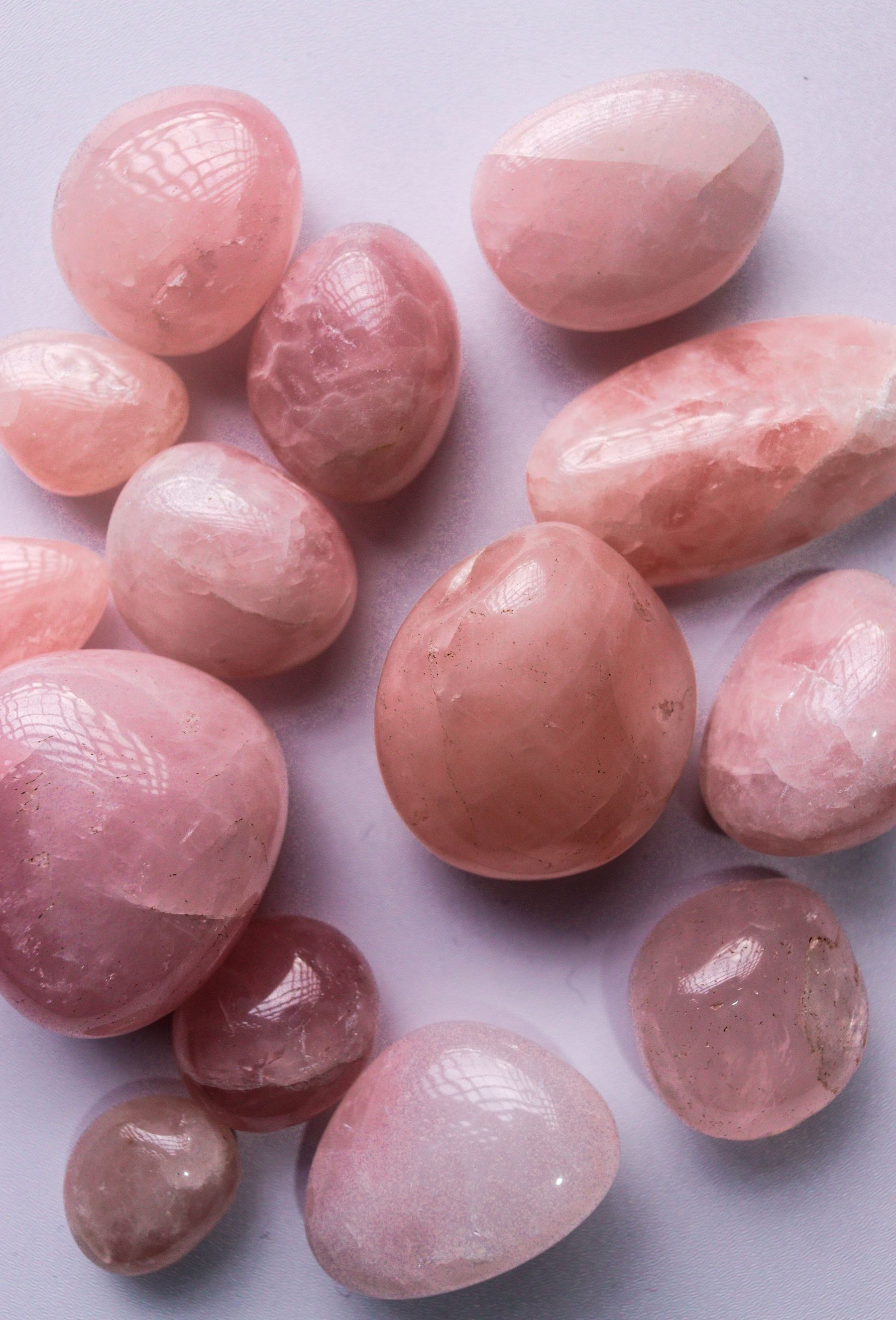 A collection of pale pink rose quartz crystals on a soft surface